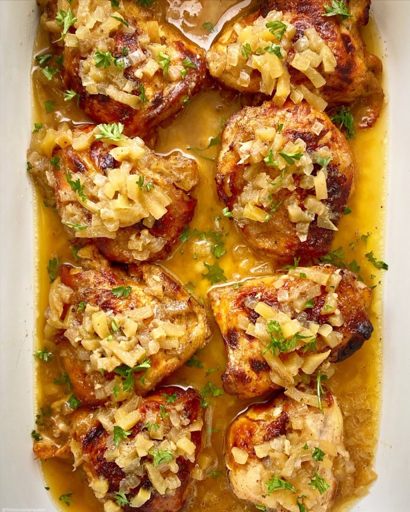 overhead shot of cooked chicken with apples and honey in a white baking dish