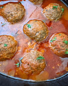 close up shot of cooked stuffed mozzarella stuffed meatballs in the slow cooker