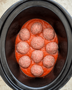 close up shot of cooked stuffed mozzarella stuffed meatballs in the slow cooker