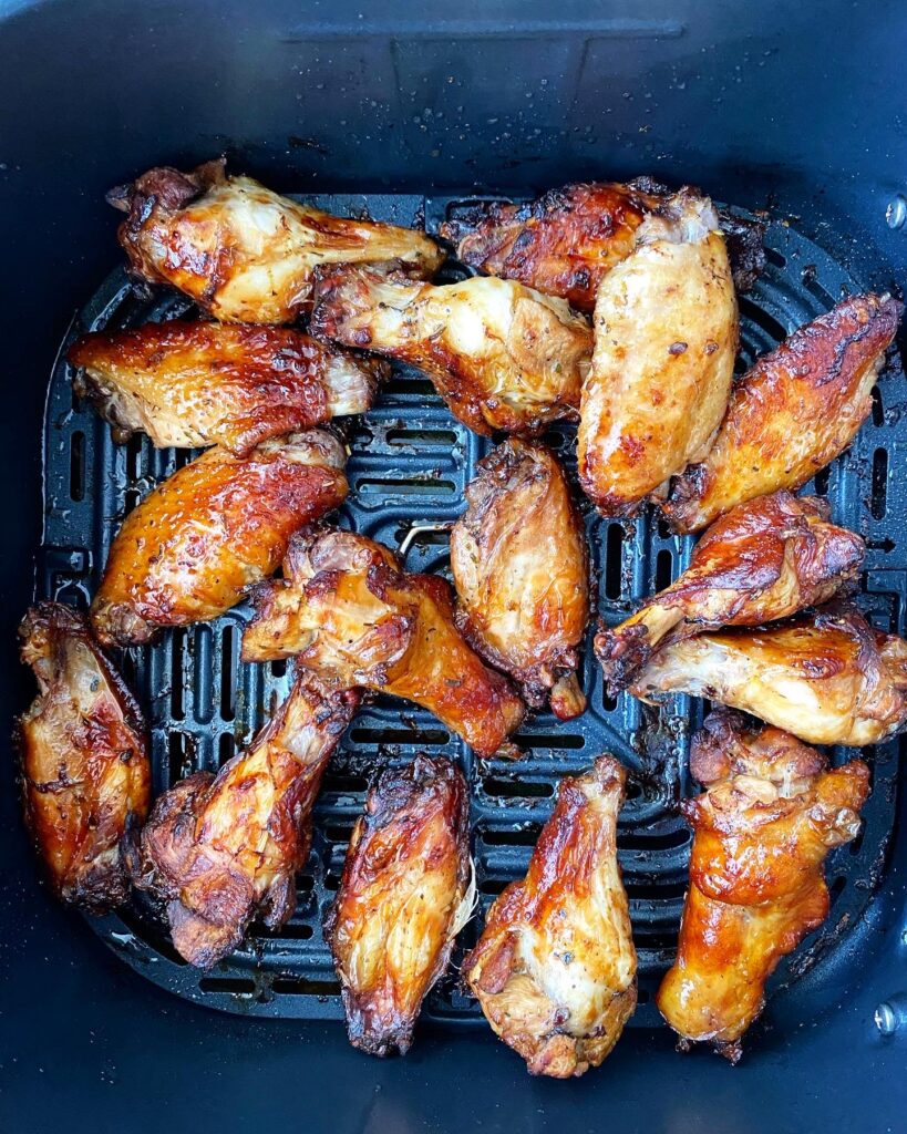 overhead shot of cooked marinated chicken wings in the air fryer basket