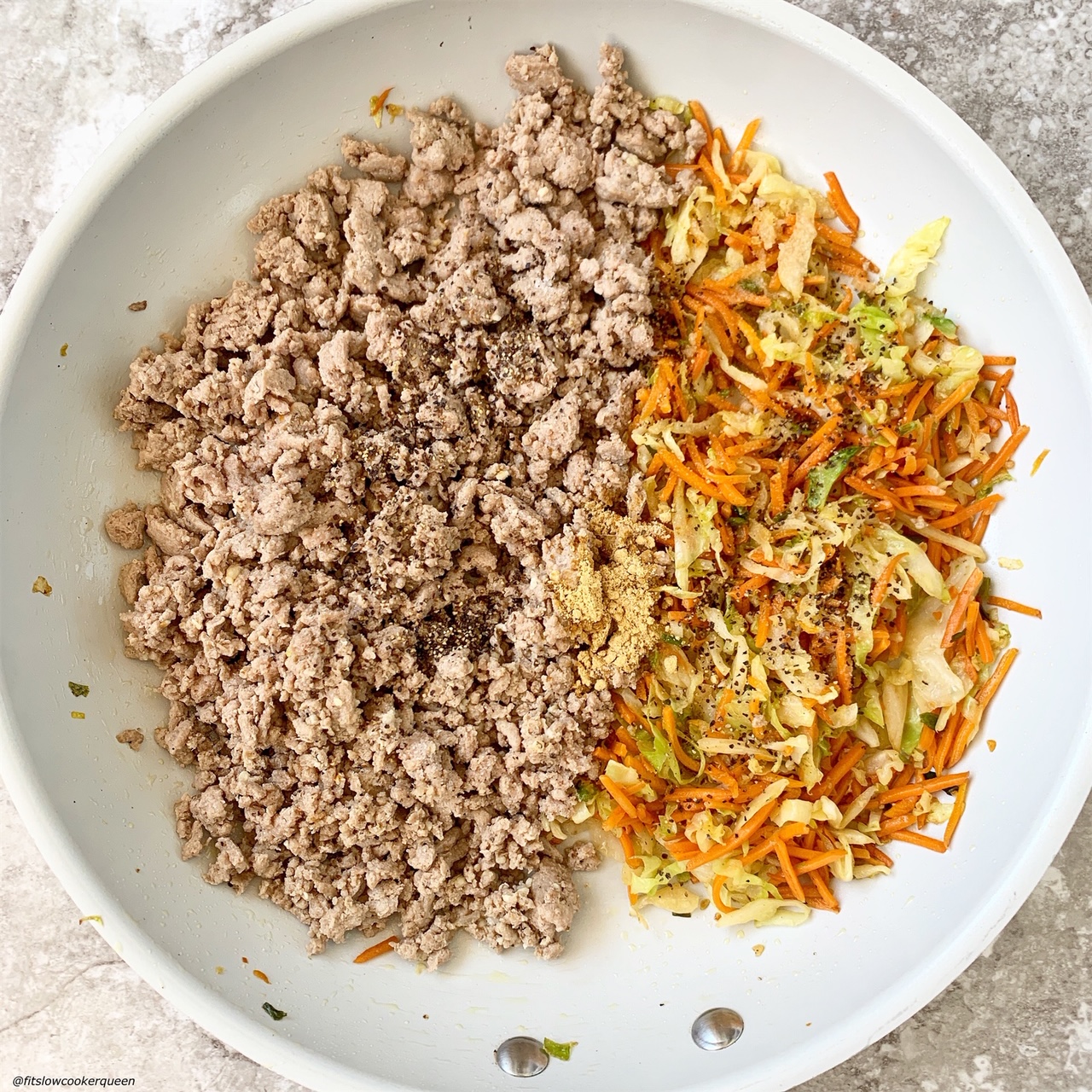 ground meat, cabbage, and carrots in a skillet with seasonings