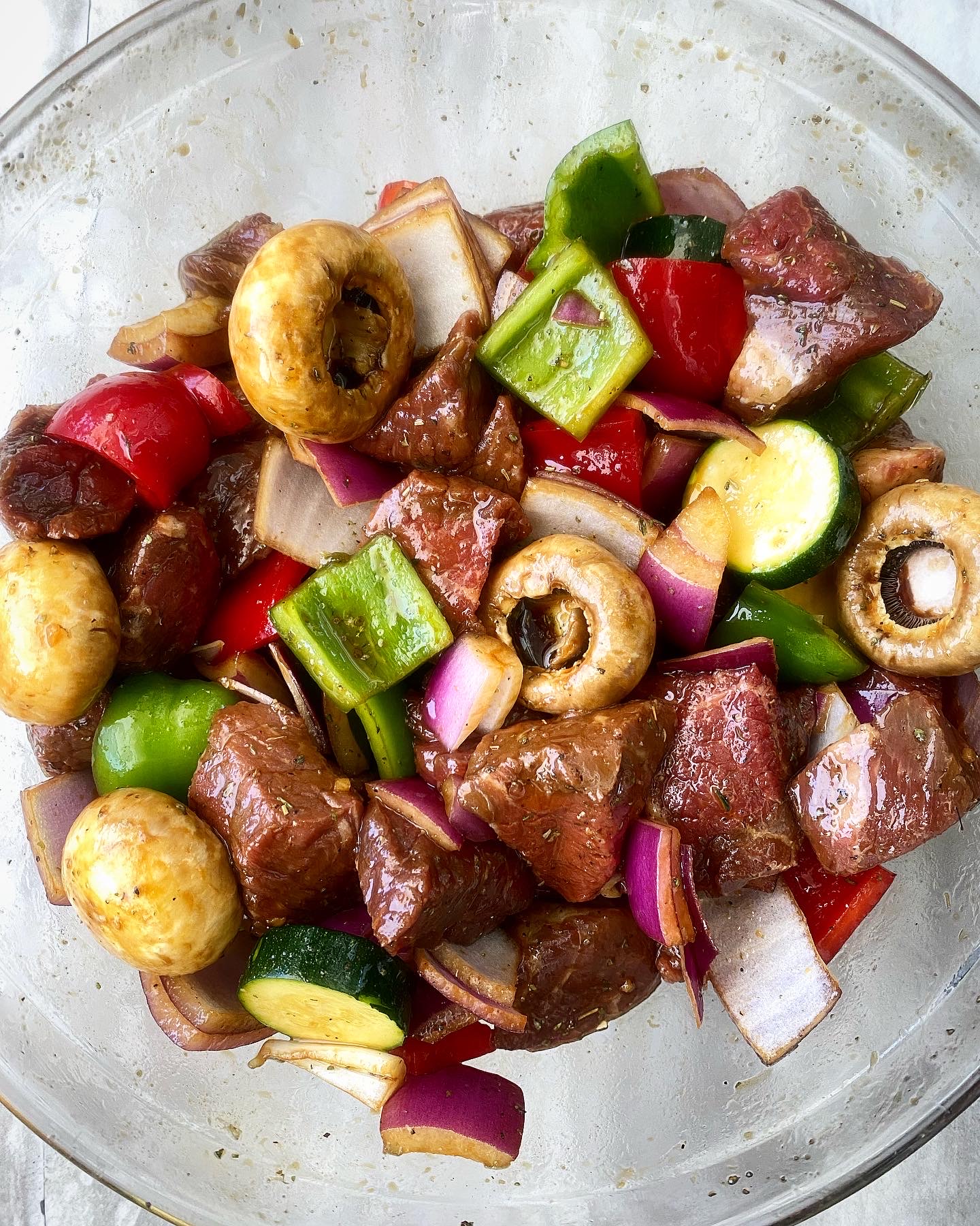overhead shot of beef & veggies in a glass bowl with marinade