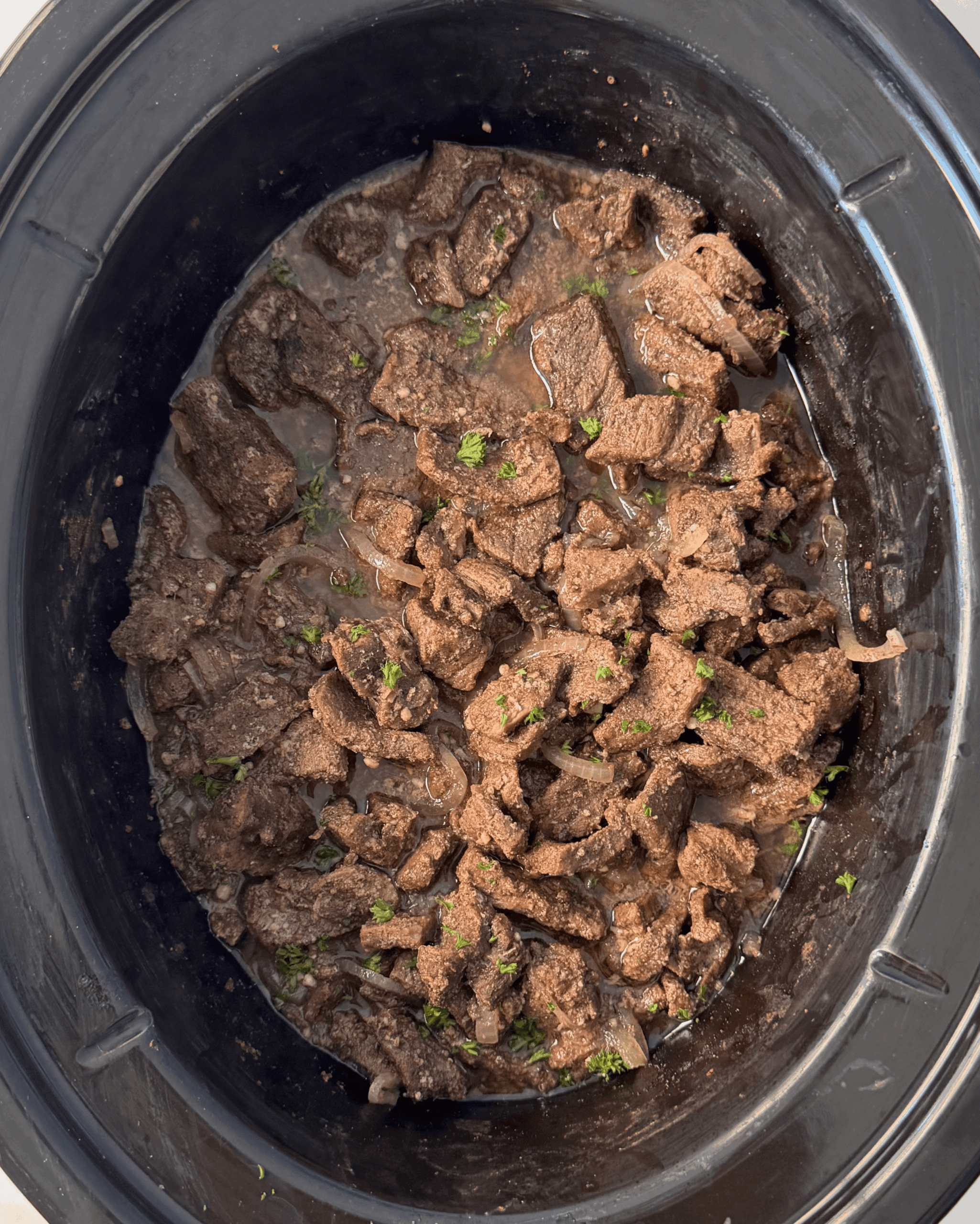 overhead shot of cooked beef shawarma in a black slow cooker