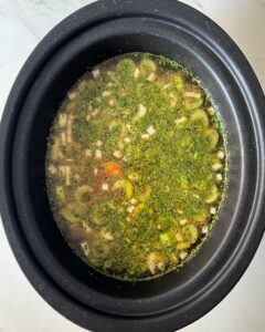 ove3rhead shot of uncooked chicken soup in a black slow cooker