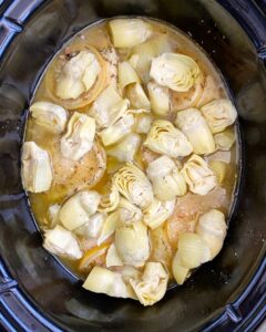 ingredients for lemon artichoke chicken in the slow cooker with artichokes on top