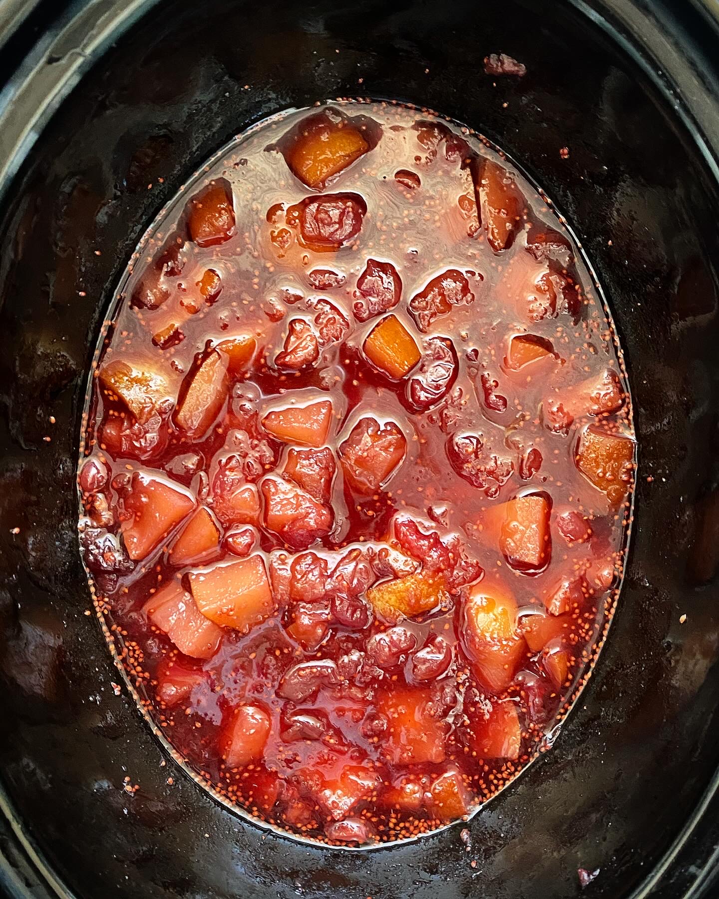 overhead shot of cooked homemade cranberry sauce in a black slow cooker