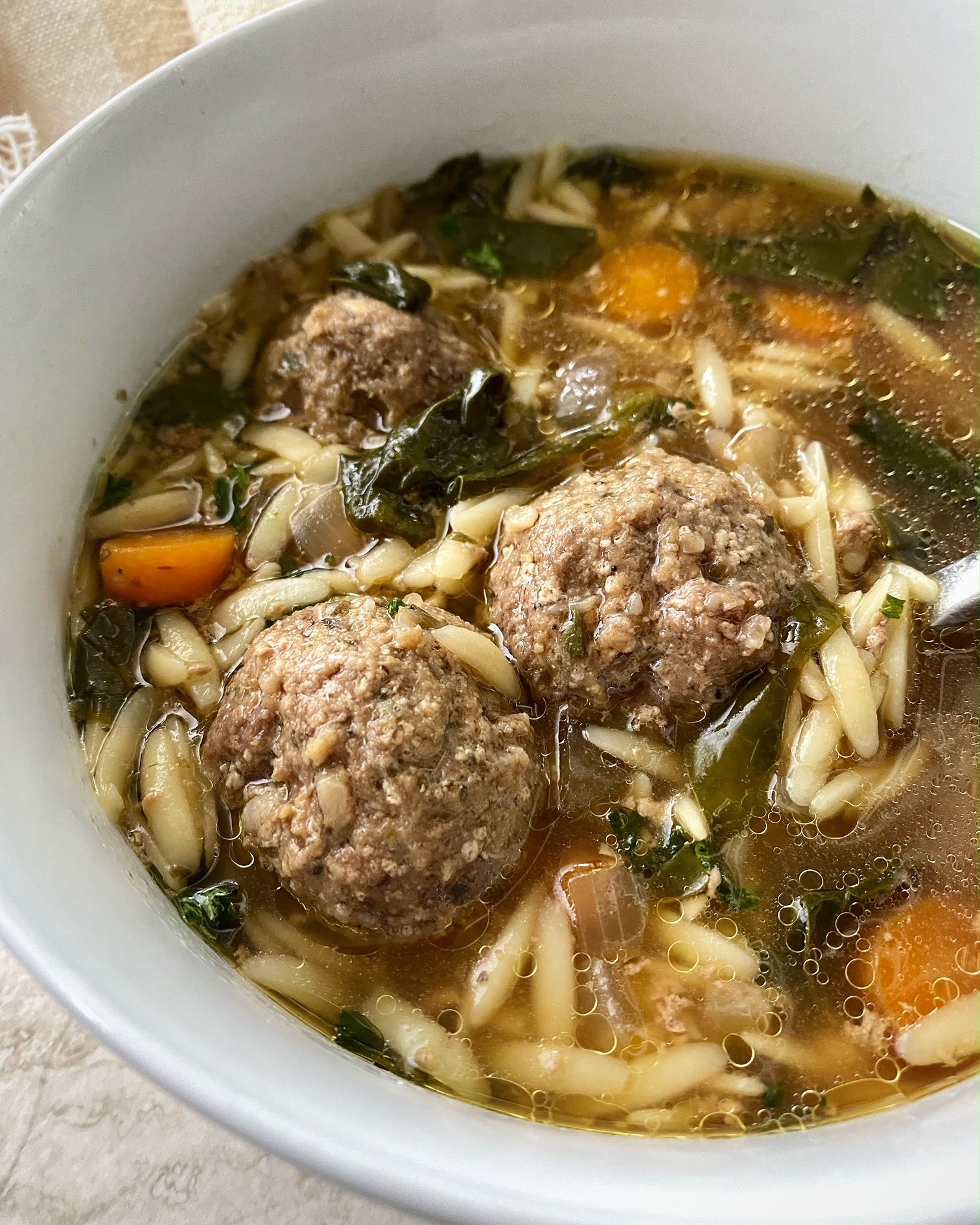 close up shot of Italian wedding soup in a white bowl