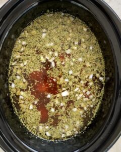 overhead shot of uncooked Italian wedding soup in a black crockpot