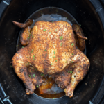 overhead shot of cooked slow cooker whole chicken in a black slow cooker