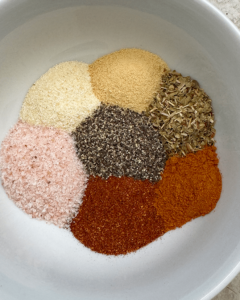 overhead shot of paprika, salt, garlic powder, onion powder, thyme, pepper, and cayenne in a white bowl