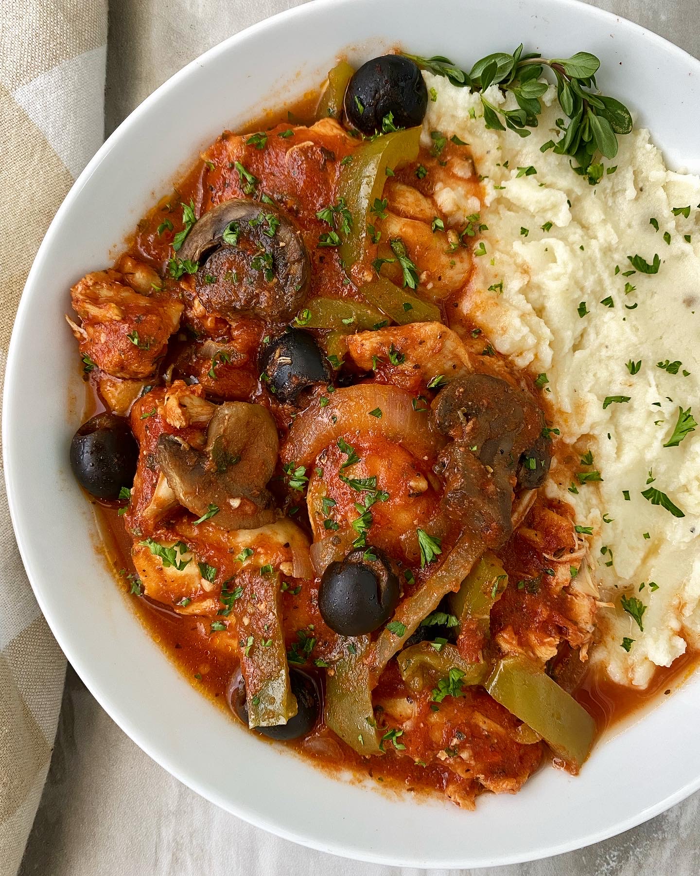 cooked chicken cacciatore in a white bowl with mashed potatoes