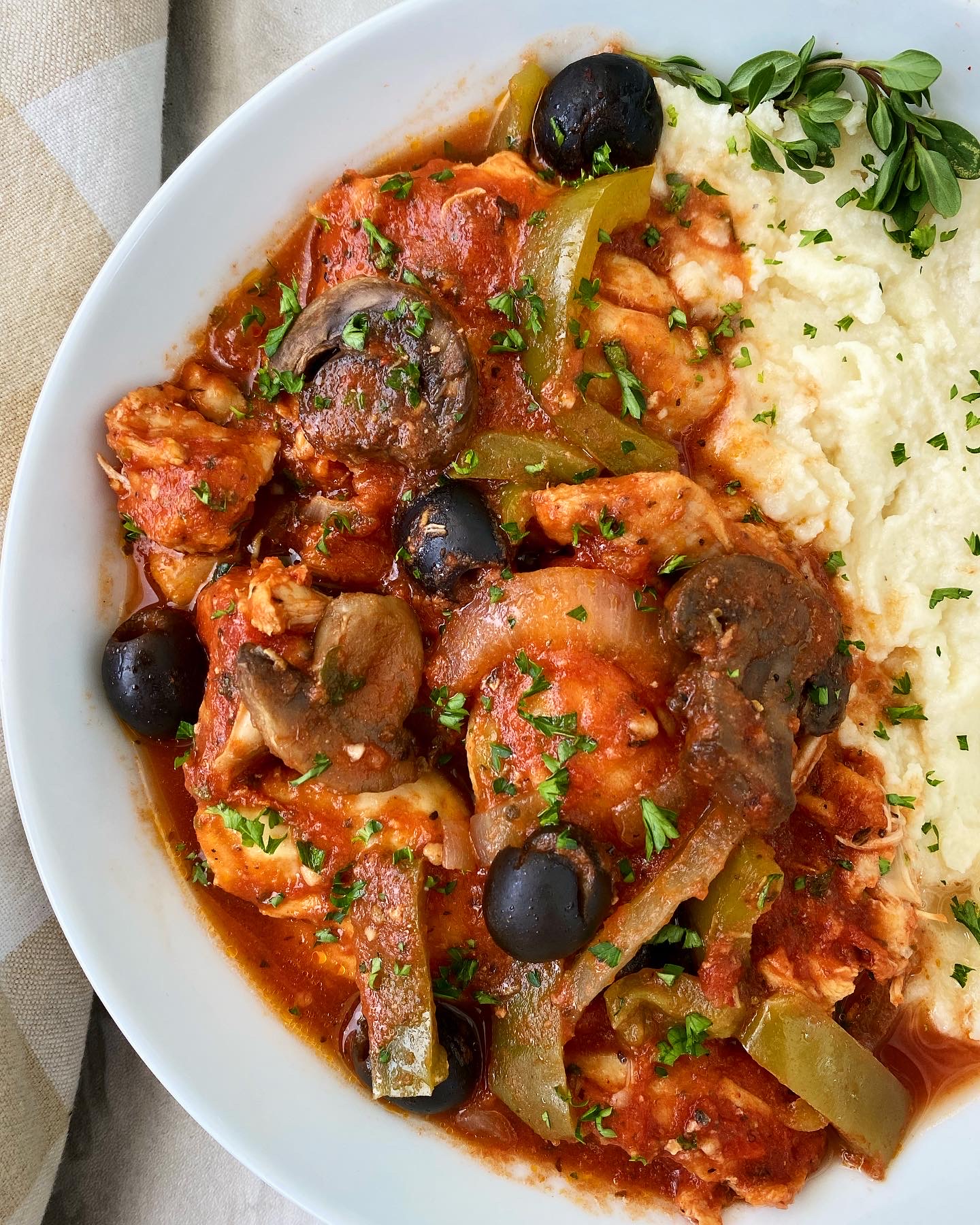 cooked chicken cacciatore in a white bowl with mashed potatoes