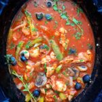 cooked chicken cacciatore in the slow cooker with fresh herbs on top