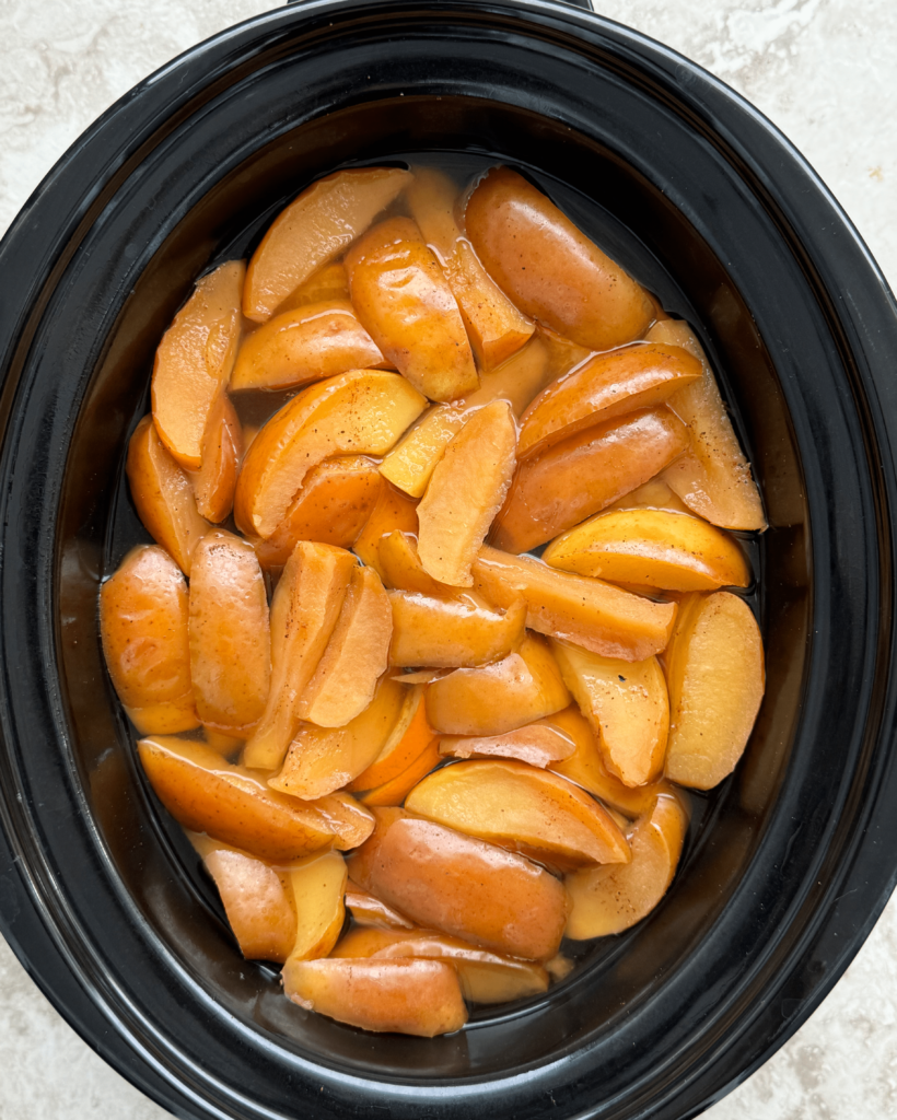 overhead shot of cooked Slow Cooker Homemade Apple Cider in a black slow cooker