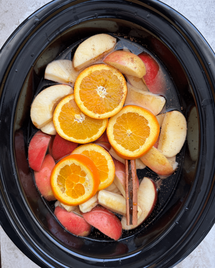 overhead shot of uncooked Slow Cooker Homemade Apple Cider in a black slow cooker