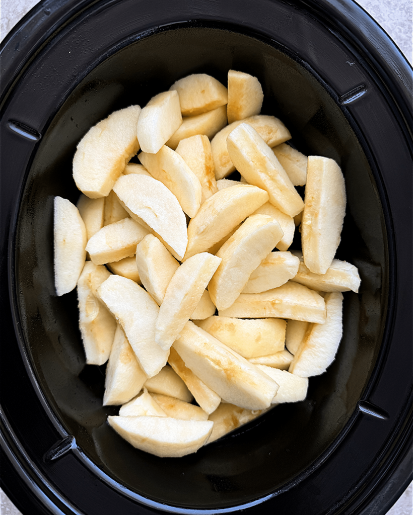 overhead shot of uncooked slow cooker unsweetened applesauce in a black slow cooker