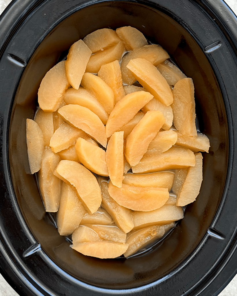 overhead shot of cooked slow cooker unsweetened applesauce in a black slow cooker