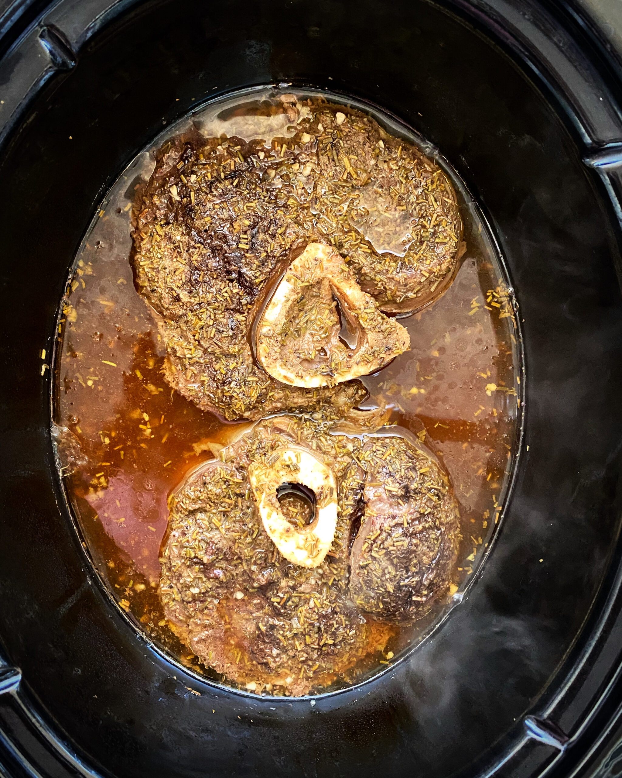 overhead shot of cooked beef shanks in a black crockpot