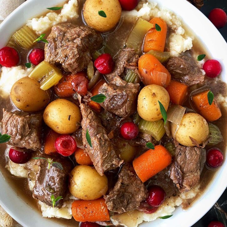 overhead shot of cooked cranberry beef stew served over mashed potatoes