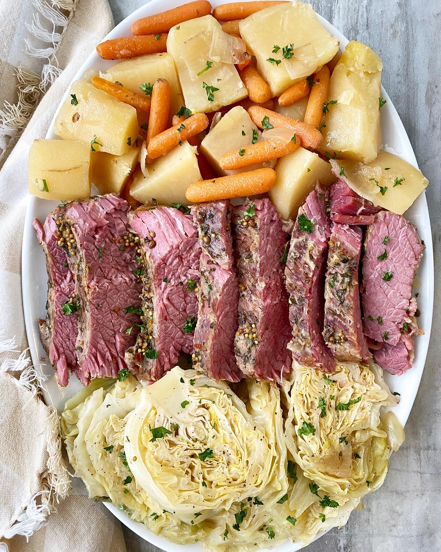 overhead shot of corned beef & cabbage with potatoes, carrots, and onion on a white platter