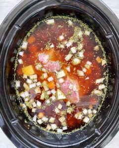 overhead shot of uncooked corned beef & cabbage soup in a black slow cooker
