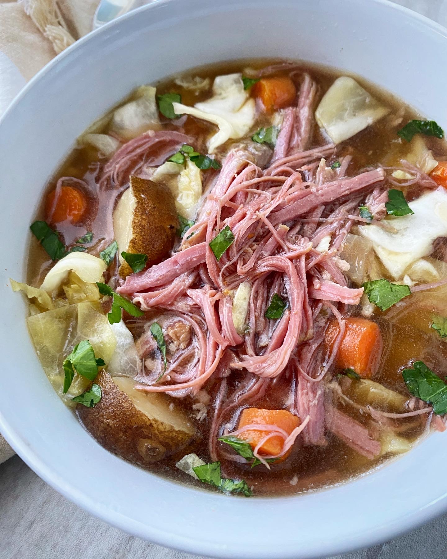 overhead shot of corned beef & cabbage soup in a white bowl