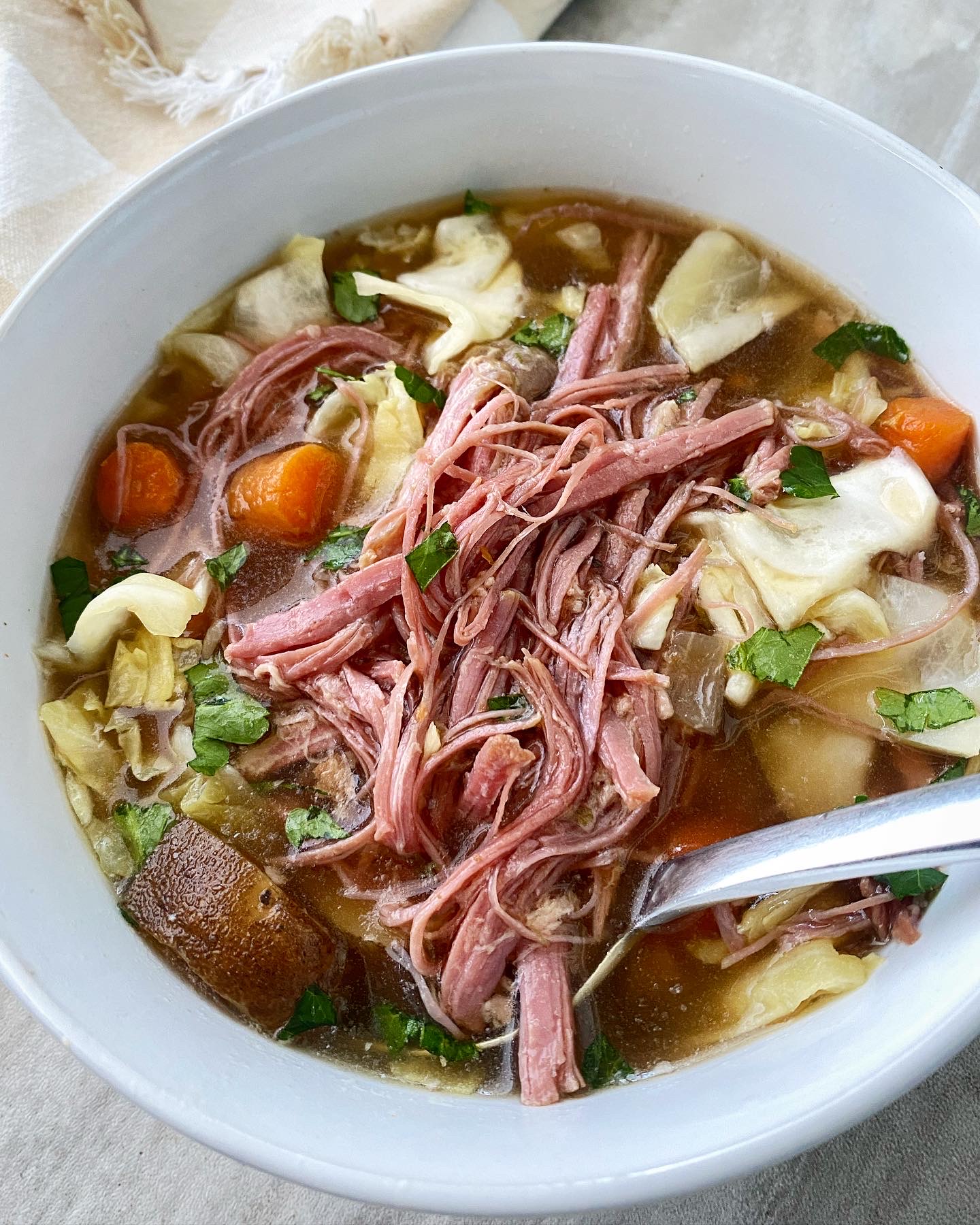 overhead shot of corned beef & cabbage soup in a white bowl