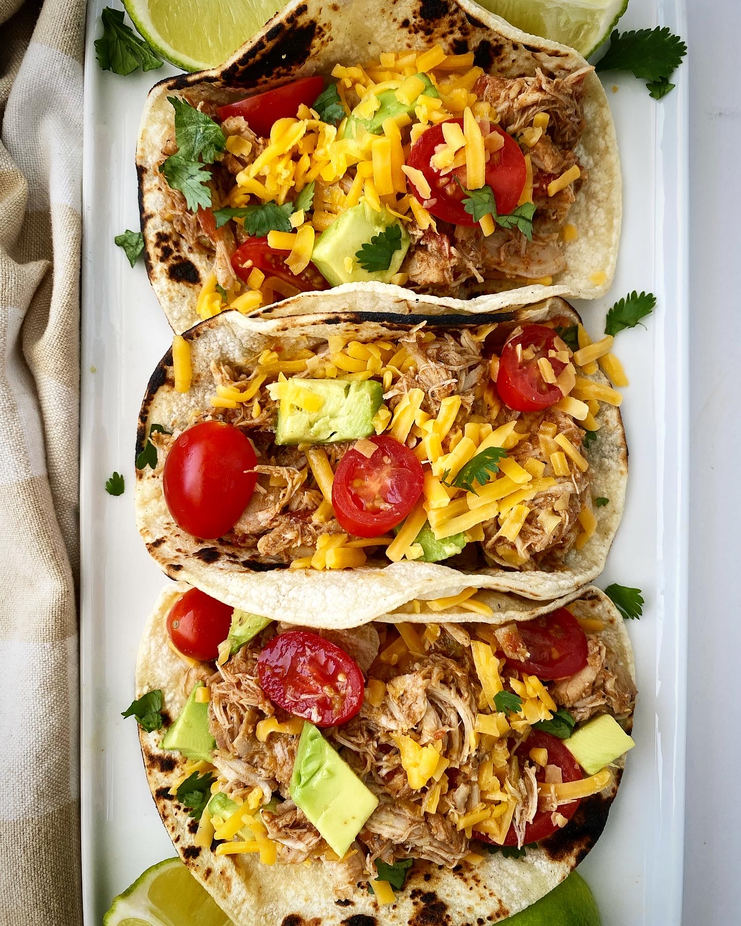 overhead shot of easy crockpot chicken tacos in tortillas on a white plate
