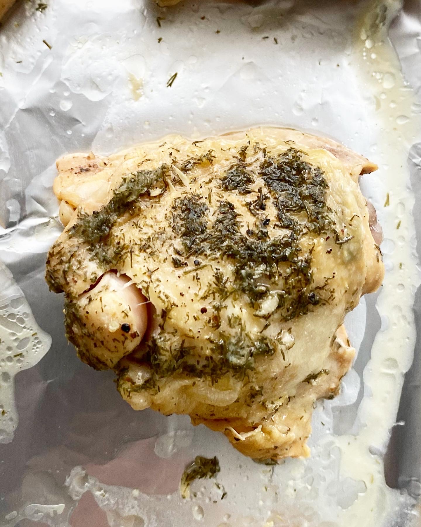 overhead shot of cooked chicken thigh on a foil-lined baking sheet