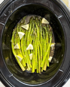 overhead shot of cooked close up shot of Slow Cooker Lemon Garlic Asparagus in a black slow cooker