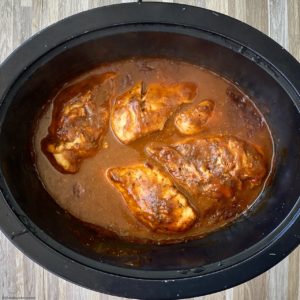 overhead shot of cooked BBQ pulled chicken in a black slow cooker