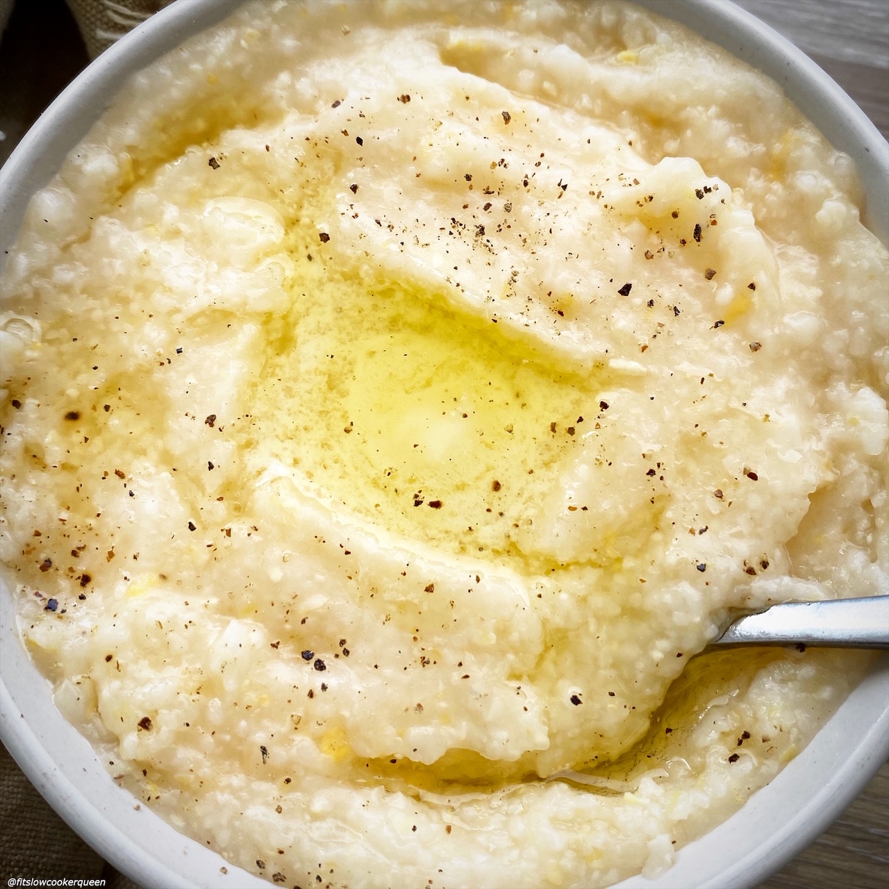 overhead shot of grits in a white bowl with butter and black pepper