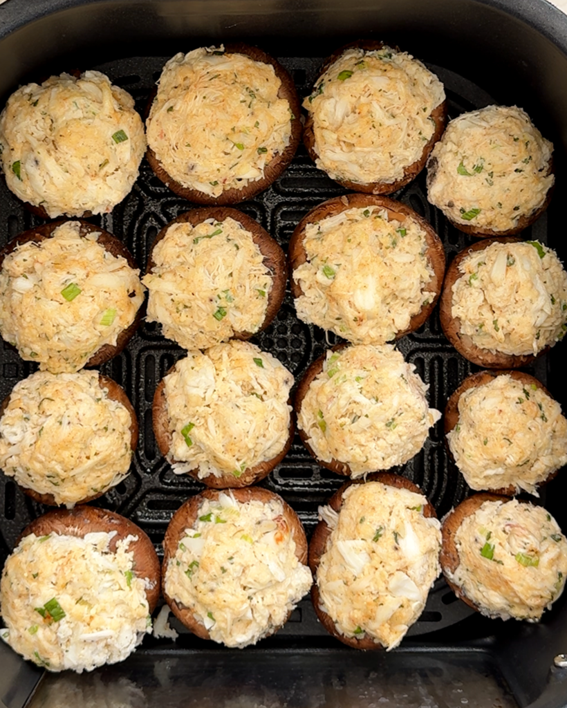 overhead shot of uncooked crab stuffed mushrooms in a black slow cooker