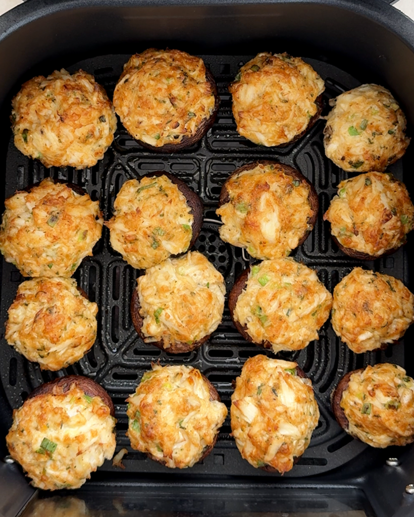 overhead shot of uncooked crab stuffed mushrooms in a black slow cooker