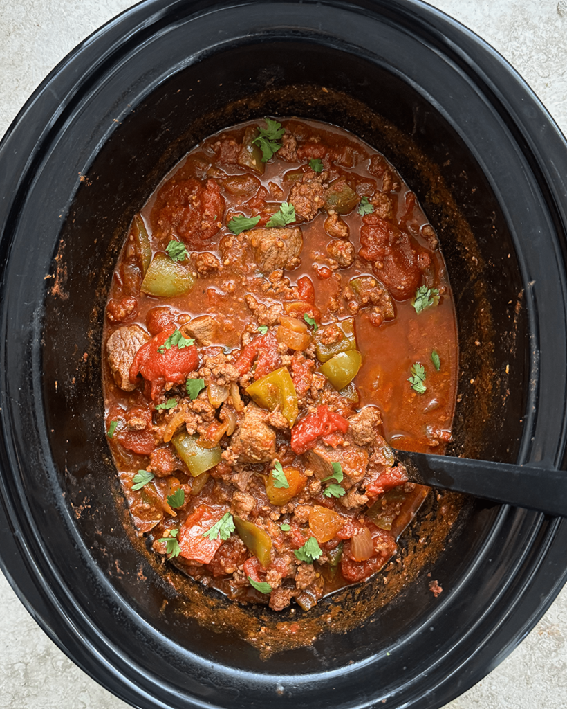 overhead shot of cooked Beef Chili Stew in a black slow cooker