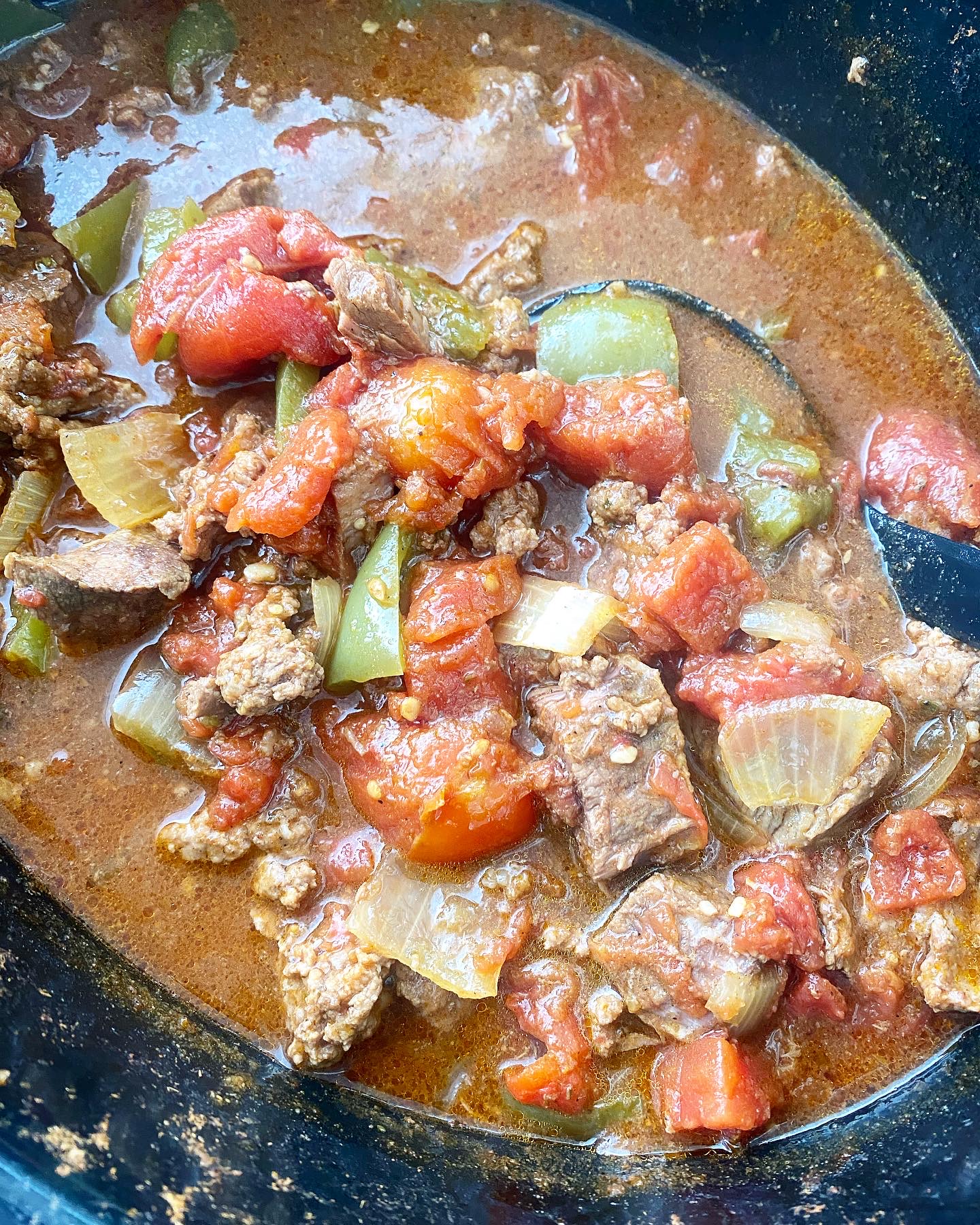 overhead shot of cooked chunky beef stew in a black slow cooker