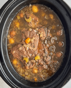 overhead shot of cooked pot roast soup in a black slow cooker