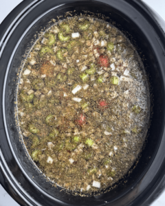 overhead shot of uncooked pot roast soup in a black slow cooker