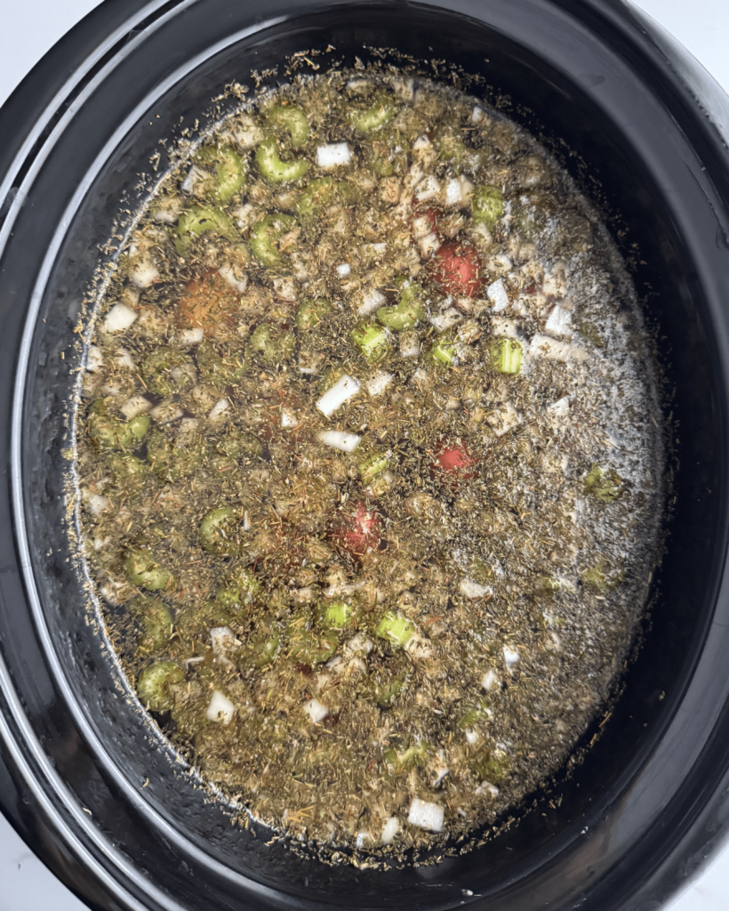 overhead shot of uncooked pot roast soup in a black slow cooker