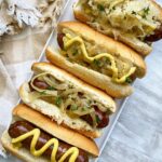 overhead shot of beer brats in buns with condiments