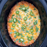 overhead shot of cooked salsa verde chicken casserole in a black slow cooker