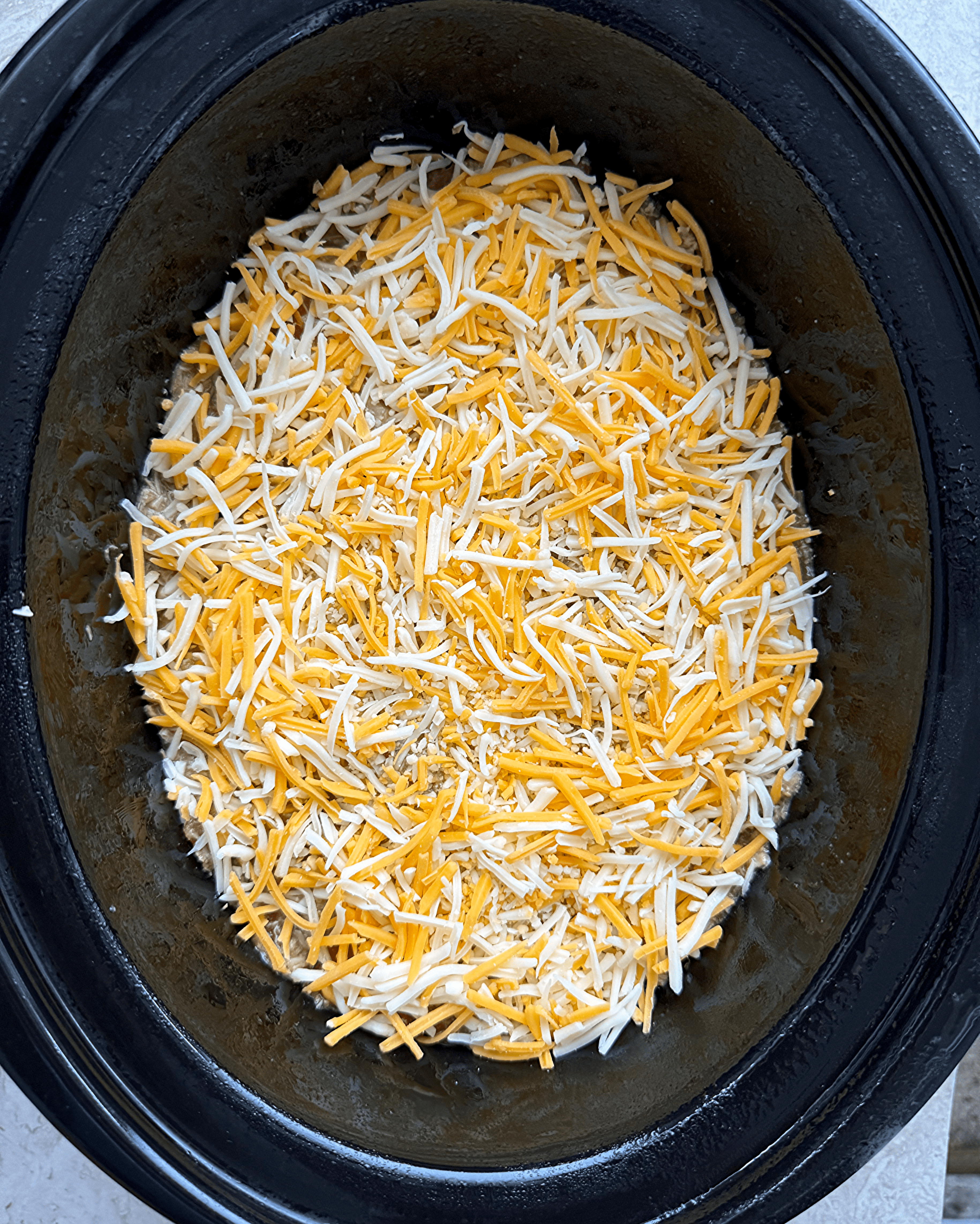 overhead shot of uncooked salsa verde chicken casserole in a black slow cooker