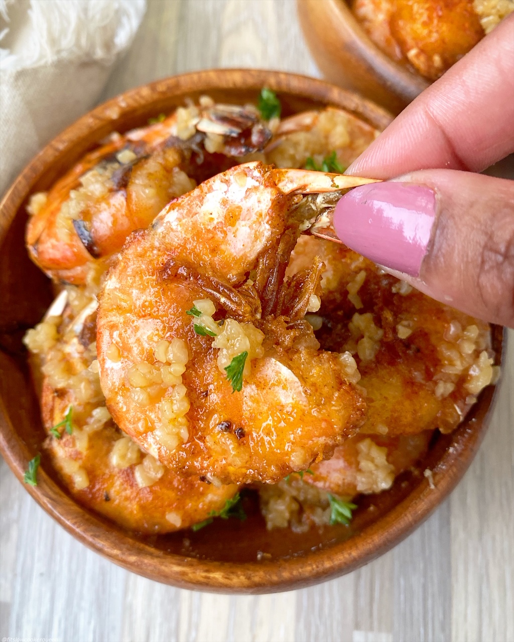 picking up a piece of cooked hawaiian garlic shrimp