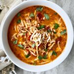 overhead shot of Caprese chicken stew in a white bowl garnished with fresh basil