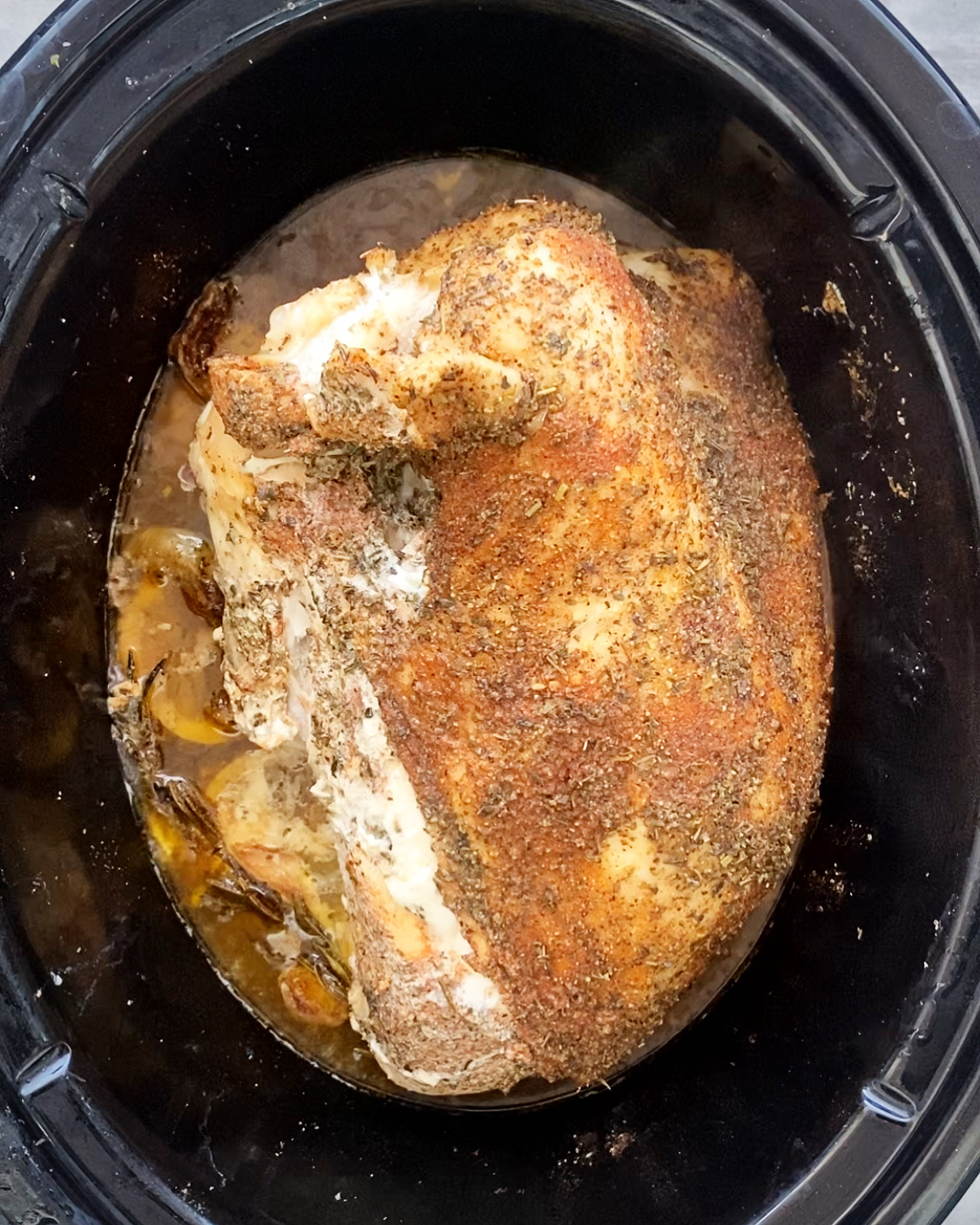 cooked turkey breast in a black crockpot