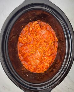 overhead shot of uncooked Buffalo Chicken Dip in a black slow cooker