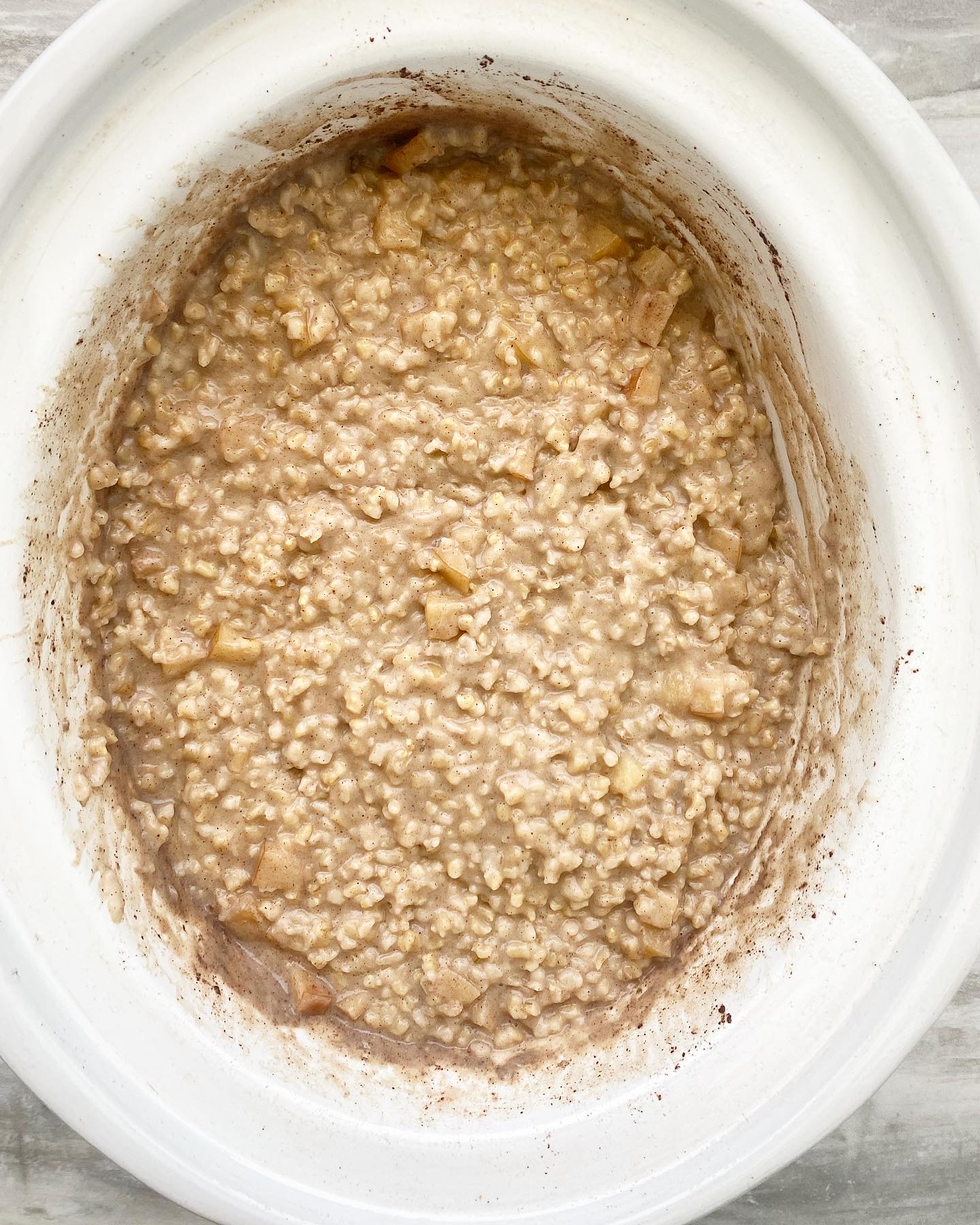overhead shot of cooked apple cinnamon oatmeal in a white slow cooker