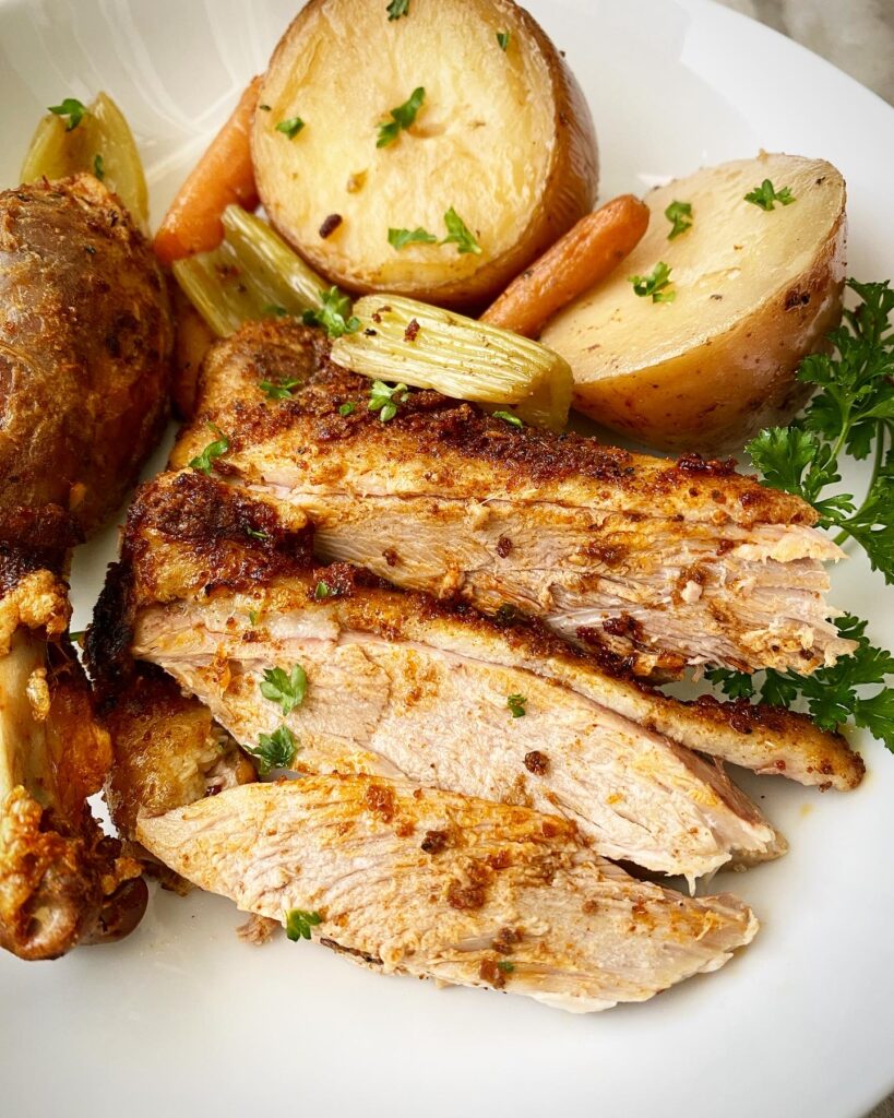 overhead, close up shot of sliced duck breast, 1 leg of duck, potatoes, celery, and carrots