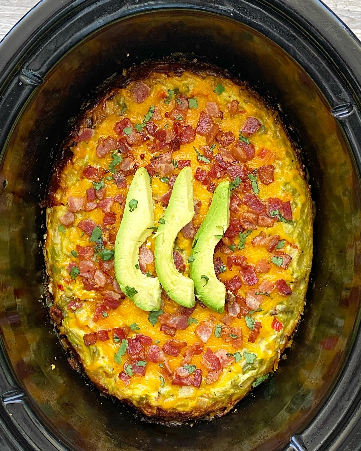 overhead shot of Bacon Avocado Breakfast Casserole in a black slow cooker