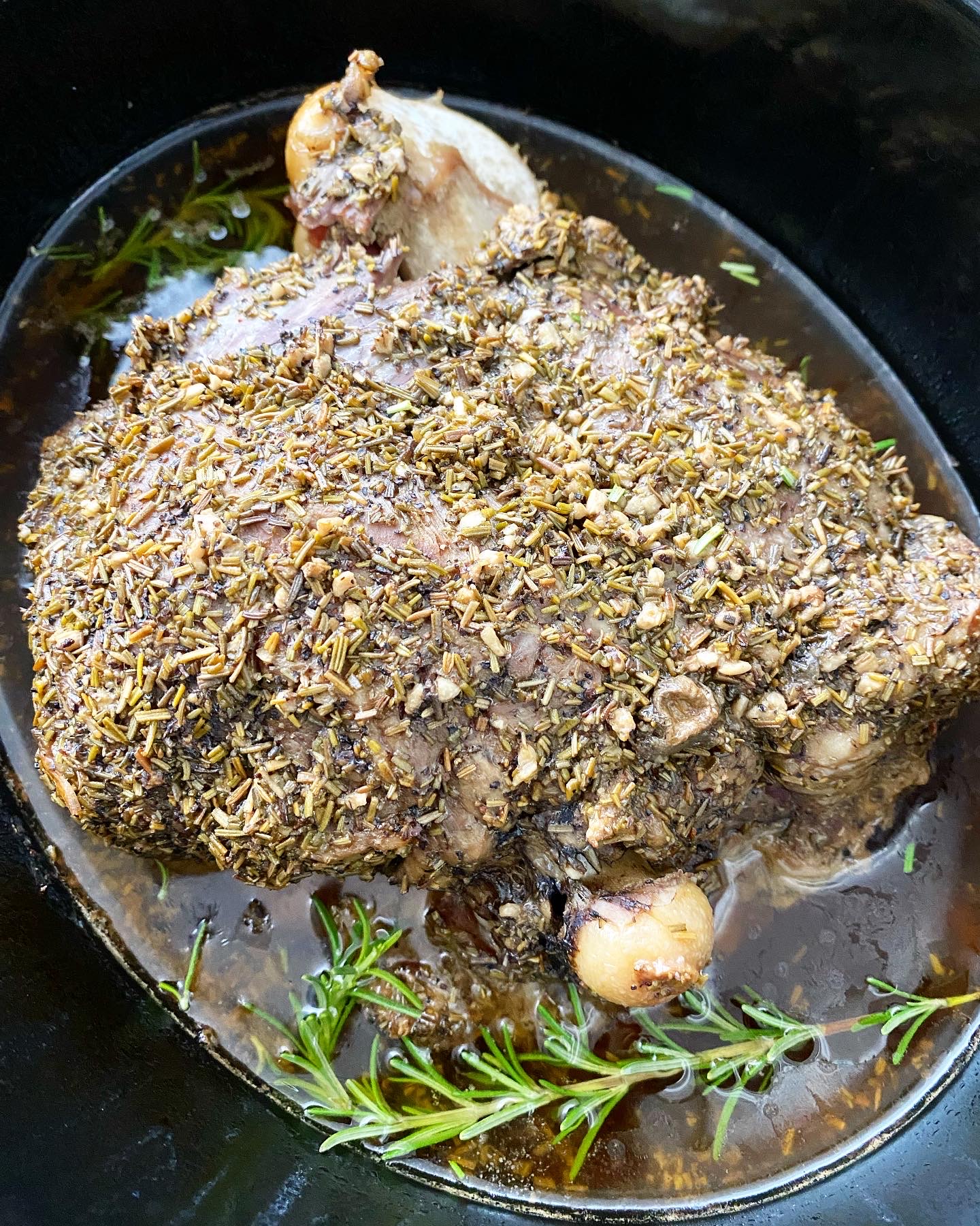 overhead shot of cooked leg of lamb in a black slow cooker